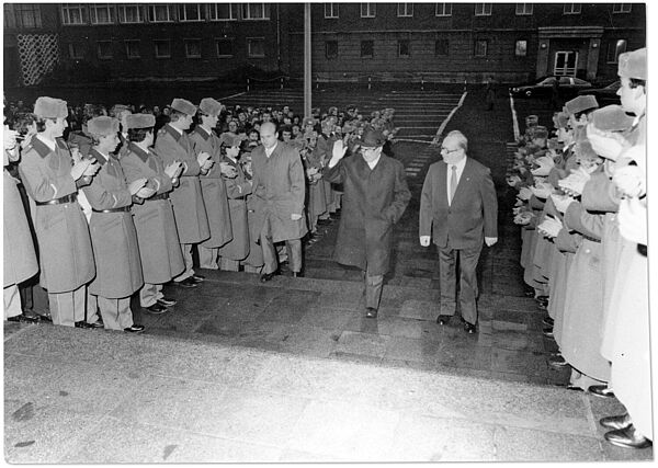 Rudi Mittig (rechts) empfängt Erich Honecker in der Stasi-Zentrale anlässlich des 75. Geburtstags Erich Mielkes, 1983; Quelle: BArch, MfS, BdL, Fo, Nr. 277, Bild 20 Rudi Mittig begleitet Erich Honecker in der Stasi-Zentrale in Berlin-Lichtenberg durch ein Spalier uniformierter Stasi-Mitarbeiter die Treppenstufen zum Offizierskasino der Stasi in Haus 22 herauf.
